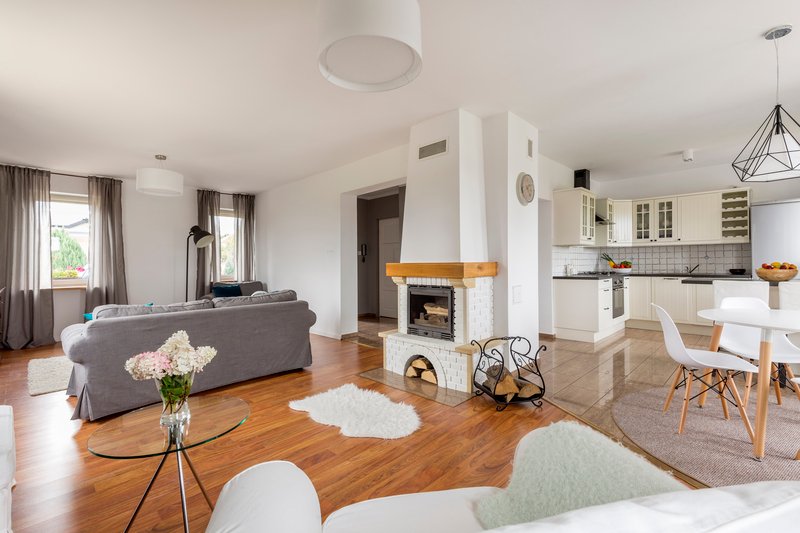 Interior de casa con sala amplia, chimenea central, comedor y cocina integrada, con iluminación natural y acabados modernos.